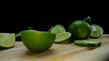 Close-up, a vibrant slice of fresh lime rests upon a rustic wooden cutting board, exuding freshness and vitality. The translucent membranes of the green lime slice placed on cutting board. Comestible.