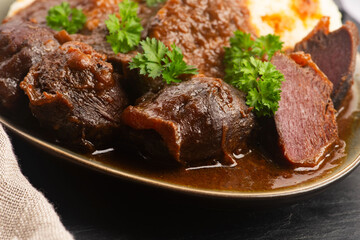 Stewed goose stomach.  Traditional Polish meat on a dark background.