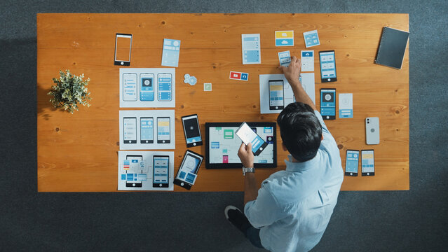 Top view of skilled developer walking and placing Ux Ui software. Smart business man put tablet on meeting table with mobile phone interface or icon. Investor plan develop software plan. Convocation.