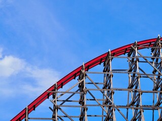 A close-up image of a red rollercoaster track and the blue sky in the background in the amusement park.