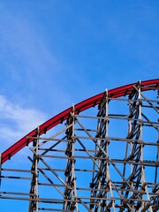 A close-up image of a red rollercoaster track and the blue sky in the background in the amusement...