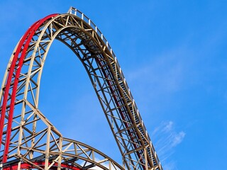 A close-up image of a red rollercoaster track and the blue sky in the background in the amusement park.