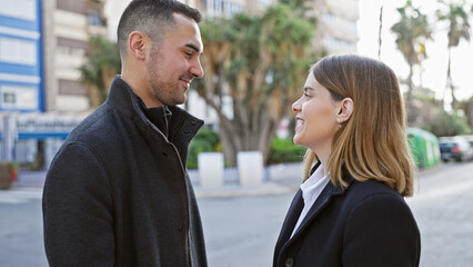 Couple in love smiling at each other on a sunny city street
