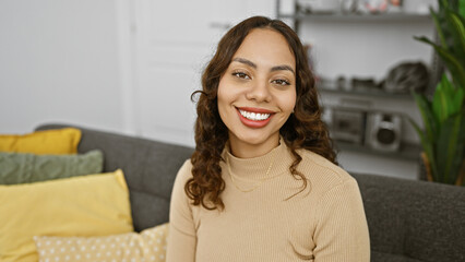 Obraz premium Smiling woman sitting on couch in modern living room interior