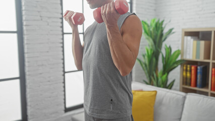 Hispanic man exercises with dumbbells in a modern indoor living room