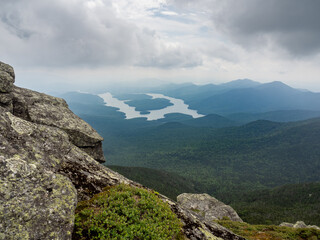 Lake Placid and East and West Lake seen from the summit of Whiteface Mountain with rocks in the foreground on a grey and gloomy day in New York State.