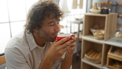 Young man enjoying a coffee in a cozy bakery shop while savoring the aroma indoors