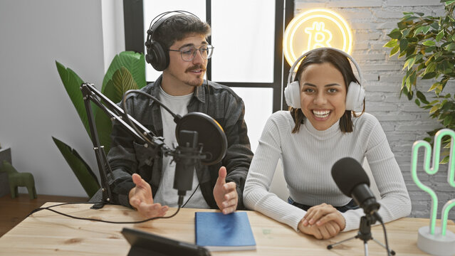 Woman and man hosting a modern podcast in a well-equipped radio studio with neon lights - Powered by Adobe