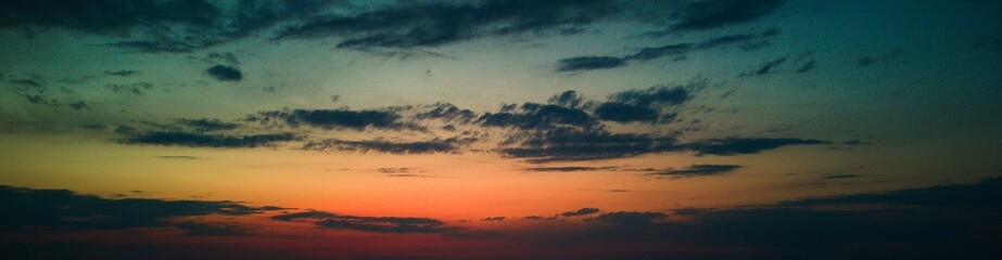 Vibrant sunset with colorful clouds over a plowed field.