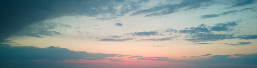 Panoramic view of a sunset over a plowed field with a dark, dramatic sky.