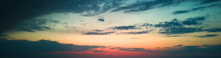 Sunset casting a warm glow over a plowed field and cloudy sky.