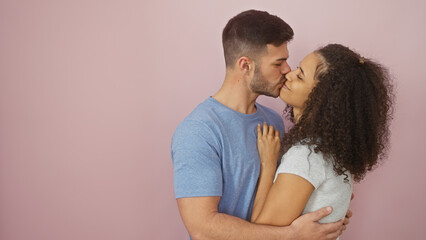 Fototapeta premium Man and woman in love sharing a tender kiss with a pink isolated background, depicting affection and relationship.