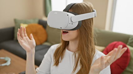 A young blonde woman experiences virtual reality indoors, expressing amazement in her living room.