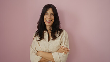 Young woman standing over isolated pink background smiling and looking confident with arms crossed.