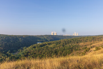 Dukovany nuclear power plant in the Czech Republic, Europe. Smoke cooling towers. There are clouds in the sky. In the foreground is the nature of the Highlands.