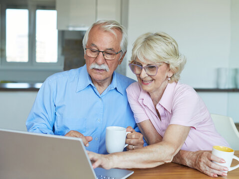 woman laptop man computer retirement senior adult couple home coffee tea cup drink table female wife husband internet elderly online communication technology