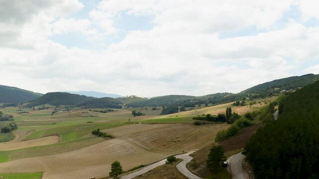 Aerial view of the wild Colfiorito Plateau in Central Italy, nestled in the Apennines between Umbria and Marche. The landscape is mostly untouched, with farmland and a few small roads