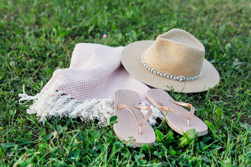 Straw hat, flip-flops and a picnic blanket on the grass. A symbol of a vacation, a great trip.