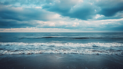 Calm ocean waves roll gently beneath a cloudy sky, offering a serene seascape.