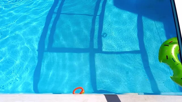 Green swimming ring floating in empty transparent swimming pool. Fresh clear water in outdoor pool. Summer time. children inflatable ring floats in pool.