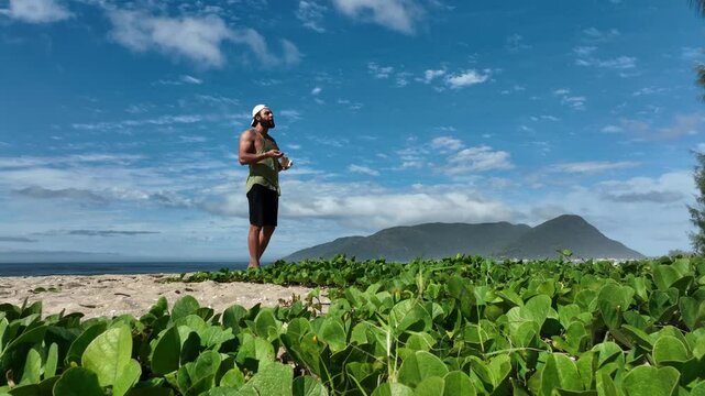 Man on a sunny day at the beach having a picnic, eating and drinking water. Outdoor concept.
