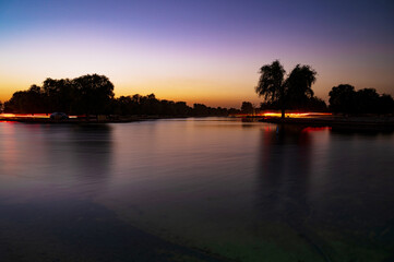 Sunset view over Love lake in the Al Qudra desert, tree silhouettes, purple and blue sky background