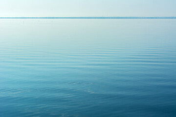 Complete calm on the water, in the sea, ocean, lake. Calm firs noticeable waves sparkle. The view...