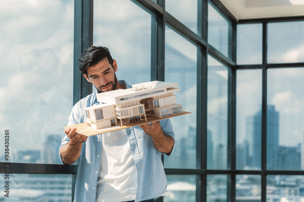 Poster handsome skilled architect engineer holds architectural model while inspect house model. professiona