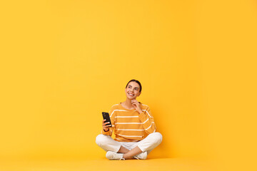 Happy woman with smartphone on yellow background
