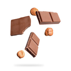 Pieces of tasty chocolate and hazelnuts falling on white background