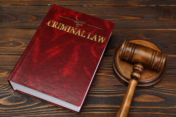 Book Criminal Law and judge's gavel on wooden table