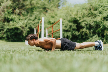 Fit man exercising in nature doing push-ups in a park, showcasing outdoor fitness and strength...