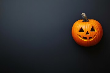 Carved pumpkin with a spooky face placed on a dark surface for Halloween