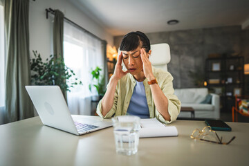mature japanese woman have headache migraine while work from home