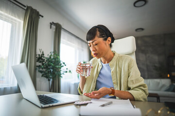 japanese woman drink the medicine with glass of water, work from home