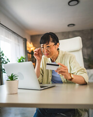 worried japanese woman buy online on laptop with credit card