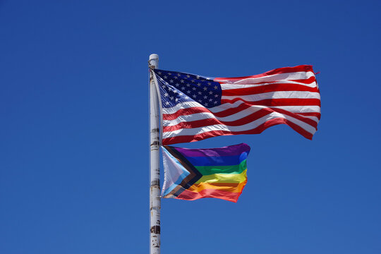 United States of America above a Rainbow Flag waving under blue sky