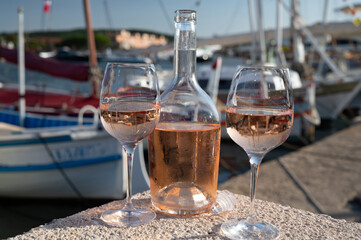 Glasses of cold rose Cote de Provence wine in old fisherman boats and yacht harbour in Saint-Tropez, summer vacation on French Riviera in Provence, France