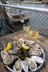Eating of fresh live oysters with citron at farm cafe in oyster-farming village, with view on boats...