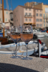 Glasses of cold rose Cote de Provence wine in old fisherman boats and yacht harbour in Saint-Tropez, summer vacation on French Riviera in Provence, France