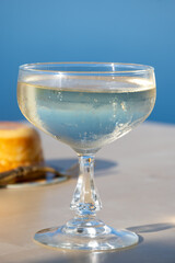 Cold sparkling wine, cava or champagne in coupe glass on table with blue sea water view