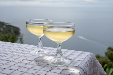 Cold sparkling wine, cava or champagne in two coupe glasses on table with sea water view