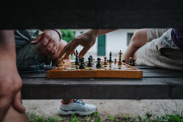 A close-up view of two people engaged in a chess game outside, showcasing strategy and...