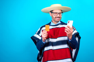hombre maduro vestido con traje tradicional huaso chileno sosteniendo un celular y tarjeta bancaria...