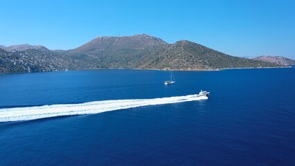 Fototapeta premium Coast guard boat heading full speed off the coast of Datça, leaving a long white trail of foam behind. Aerial a fast powerboat of Turkish Customs training and sailing in Mediterranean Sea. 