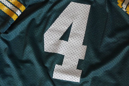 Number 4 is displayed up close on a green, white, and yellow mesh sports jersey.