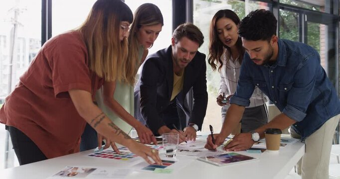 Designer, team and planning for color sample, talk or choice with writing notes in office. Men, women and graphic design for strategy, creativity or collaboration with brainstorming at startup agency