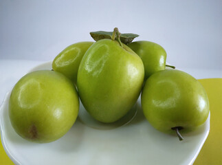 Fresh green chinese dates on white plate.