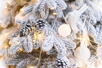 Close up of white decorations on artificial white Christmas tree with with snow.