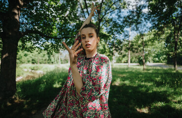 A young girl in a floral dress performing modern dance in a natural setting, surrounded by trees and lush greenery.